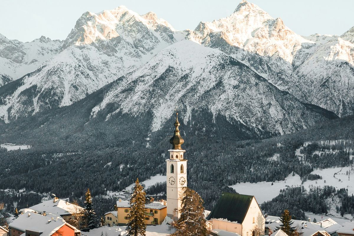 Verschneites Engadiner Dorf mit Kirchturm im Morgenlicht